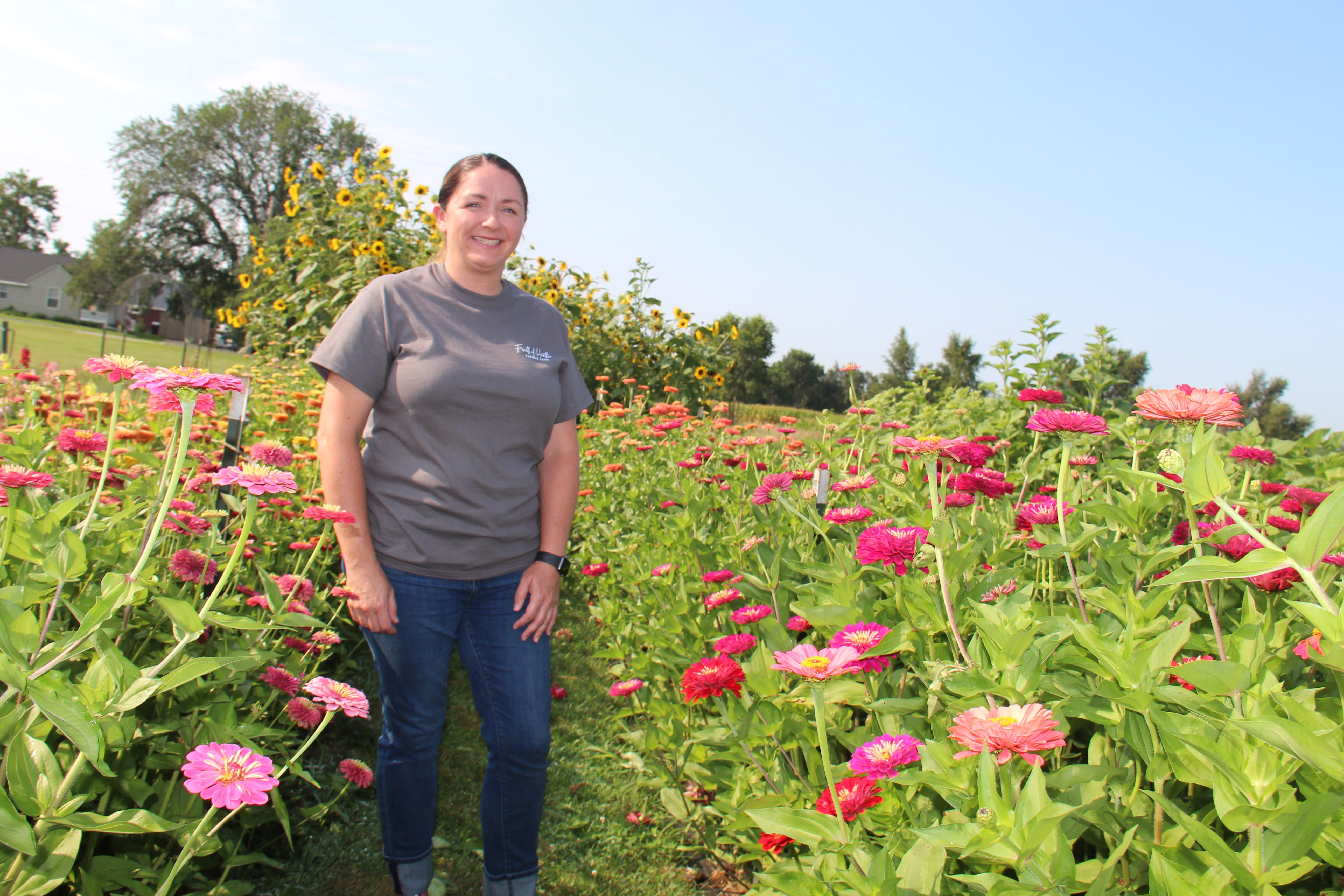 Heather Moore poses for a photo amid the zinnias growing at Fields of Heather Flower Farm in Perry.